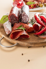 delicious meat platters served with rosemary and chili pepper on wooden board on beige background