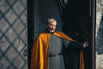 Naklejka premium Portrait of a medieval senior warrior man in armor after a battle with dirty and blood-smeared face