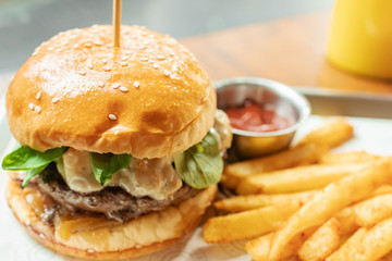Hamburger with beef burger cutlet, blue cheese, spinach, french fries and ketchup served on tray.