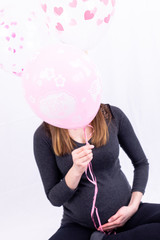 Fototapeta premium Young pregnant woman sitting with balloons - Gender Reveal - It's a Girl !