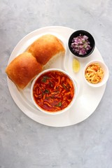Spicy Misal Pav or usal Pav is a traditional snack or Chat food from Maharashtra, India. Served with chopped onion, lemon wedges and farsan. Selective focus with copy space