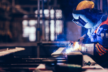 Worker welding in a factory. - obrazy, fototapety, plakaty