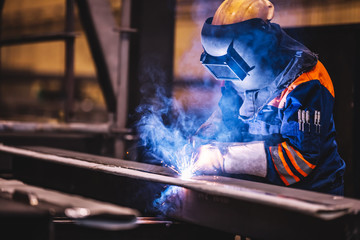 Worker welding in a factory. - obrazy, fototapety, plakaty