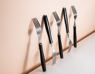 Forks standing on a wall, with big shadows between them. Silverware and their shadows on the wall