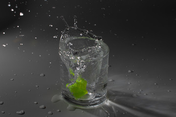 Colorful cubes dropped in a glass full of water, making beautiful splashes and wetting the table