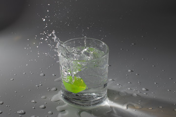 Colorful cubes dropped in a glass full of water, making beautiful splashes and wetting the table