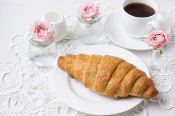 Breakfast, croissant with coffee and flowers.