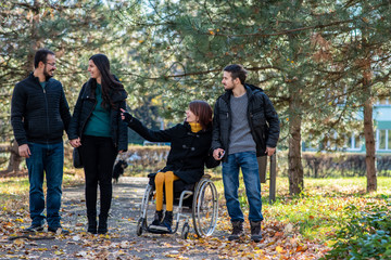 Young disabled woman in a wheelchair with friends in a park