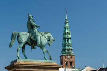 Fototapeta na wymiar Copenhagen / Denmark 07.03.2015.Statue of King Frederick VII on horseback, and view of the Spire of ancient St. Nicholas church, now St Nicolaj Kunsthal