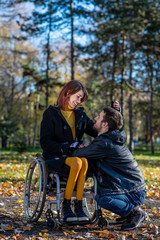 Young disabled woman in a wheelchair with boyfriend. Man with disabled girl in a wheelchair