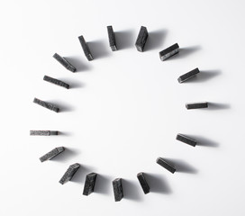 Black pieces of dominoes, arranged in a circle, seen from above