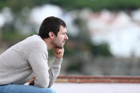 Worried man thinking looking away sitting on a bench