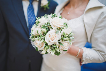 Close-up bouquet of roses of pastel shades in the hands of an unrecognizable girl. Selective focus.
