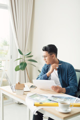 Profile shot of a young male architect working on blueprints at his desk at the office copyspace building plans construction project engineer expert specialist qualified job occupation