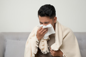 Sick man  blowing nose and sneeze into tissue. Male have flu, virus or allergy respiratory