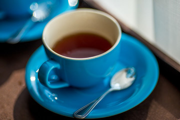 Close-up view of the blue coffee mug, clear glass for drinking water, placed on a tray to bring clear drinks, seen at resorts, hotels or bakeries