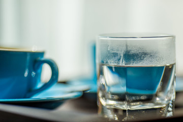 Close-up view of the blue coffee mug, clear glass for drinking water, placed on a tray to bring clear drinks, seen at resorts, hotels or bakeries