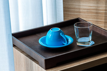 Close-up view of the blue coffee mug, clear glass for drinking water, placed on a tray to bring clear drinks, seen at resorts, hotels or bakeries