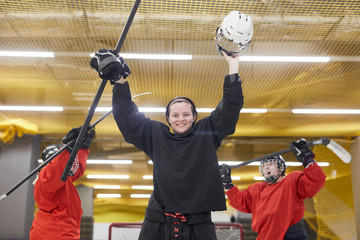 Portrait of female hockey team cheering while celebrating victory on skating rink, copy space