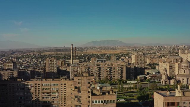 Aerial drone shot of Yerevan suburban area and mountains on background in Armenia. Drone shot of suburban area in Yerevan under bright blue sky
