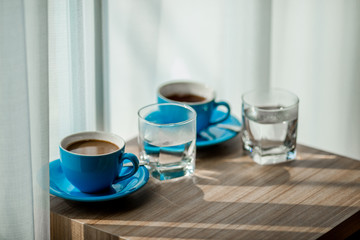 Close-up view of the blue coffee mug, clear glass for drinking water, placed on a tray to bring clear drinks, seen at resorts, hotels or bakeries