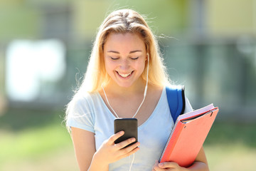 Happy student girl listening to music checks phone