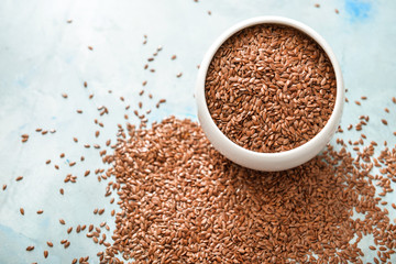Bowl with flax seeds on color background