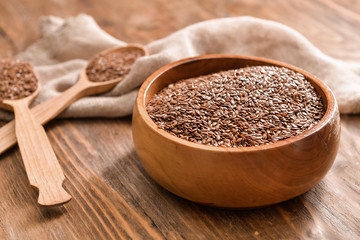 Bowl with flax seeds and spoons on wooden background