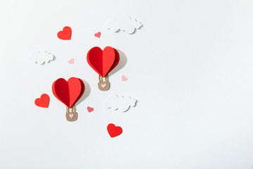 top view of paper heart shaped air balloons in clouds on white background