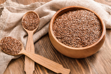 Bowl with flax seeds and spoons on wooden background