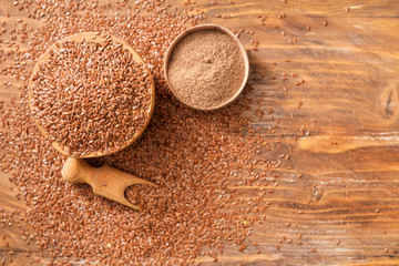 Bowls with flax seeds, powder and scoop on wooden background