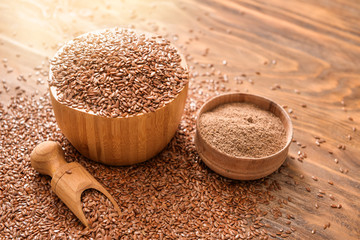 Bowls with flax seeds, powder and scoop on wooden background
