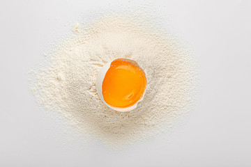 Raw chicken egg and flour on white background