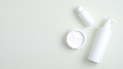 Skincare cosmetic product containers branding mockup. Top view plastic bottle with pump, cream jar, essential oil for hand. Flat lay minimalist style composition