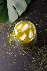 matcha tea in a glass with a double bottom on a black background. vertical image with copy space