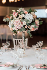 Floral arrangement of various soft pink and white flowers in the center of the festive table in a restaurant