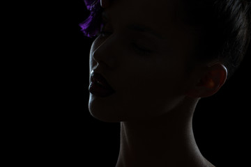 Fashion studio closeup portrait of young woman in the dark. Face of beautiful young woman.