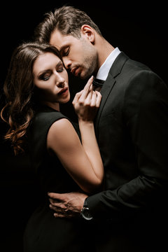 handsome man hugging young attractive woman isolated on black