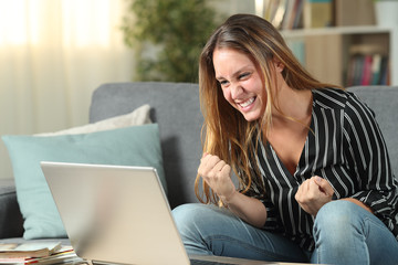 Euphoric woman celebrating success checking laptop content