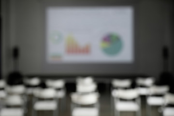 Blurred view of empty conference room with chairs and projector screen