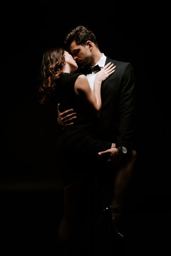 handsome man hugging sensual woman in dress isolated on black