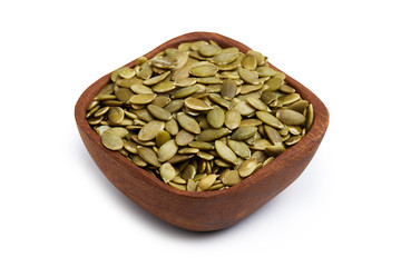 Raw shelled pumpkin seeds in wooden bowl isolated on white background