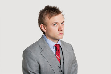 Portrait of angry young businessman over light gray background