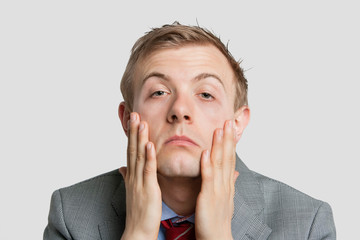 Portrait of tired young businessman over light gray background