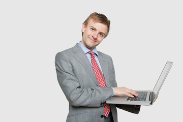 Handsome young businessman using laptop over colored background