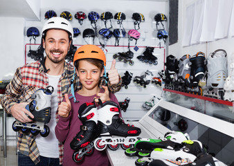Father and son showing roller-skates they bought in sports store