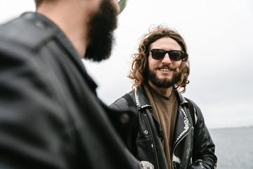 Fototapeta premium Photo of bearded joyful men bikers smiling and talking while standing
