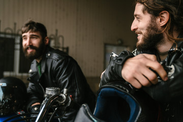 Obraz na płótnie Canvas Photo of men bikers talking and smiling while sitting on their bikes