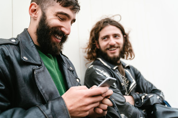 Fototapeta premium Photo of bearded joyful men bikers using cellphone and smiling