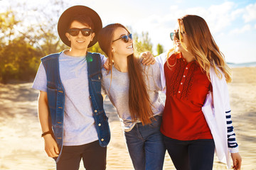 Group of happy friends spending time together at the beach. Young friends are having fun at sunset on the beach. Group of smiling people in sunglasses enjoy photos. Summer, holidays, vacation concept 